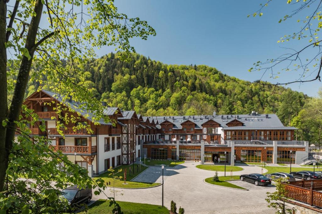 什恰夫尼察Szczawnica Park Resort & Spa的一座大建筑,背景是一座山