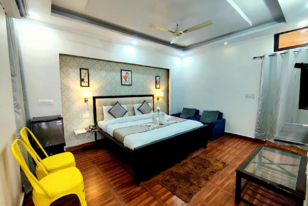 巴雷利Hotel Krishna Residency Bareilly Near Ashish Royal Park的一间卧室配有一张床、一张桌子和黄色的椅子