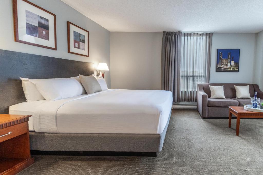 蒙特利尔Hôtel Saint-Laurent Montréal的酒店客房设有一张大床和一张沙发。