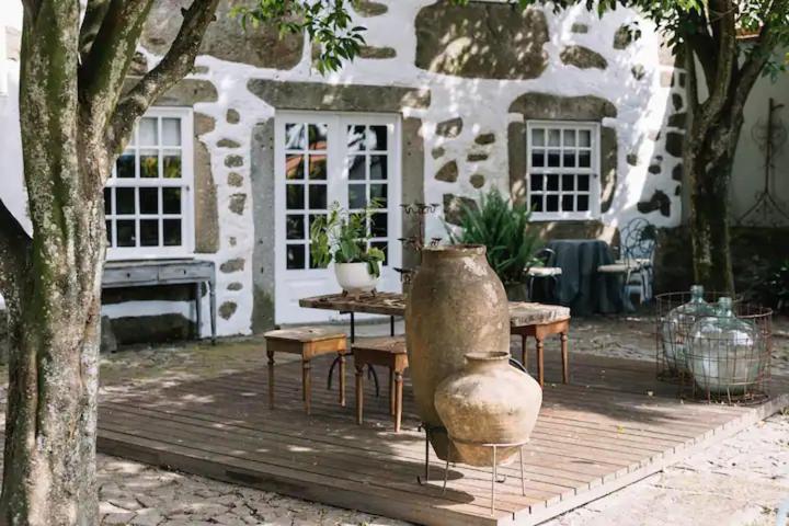 布拉加Casa da Pedra Cavalgada的一座建筑前的庭院,配有桌子和花瓶