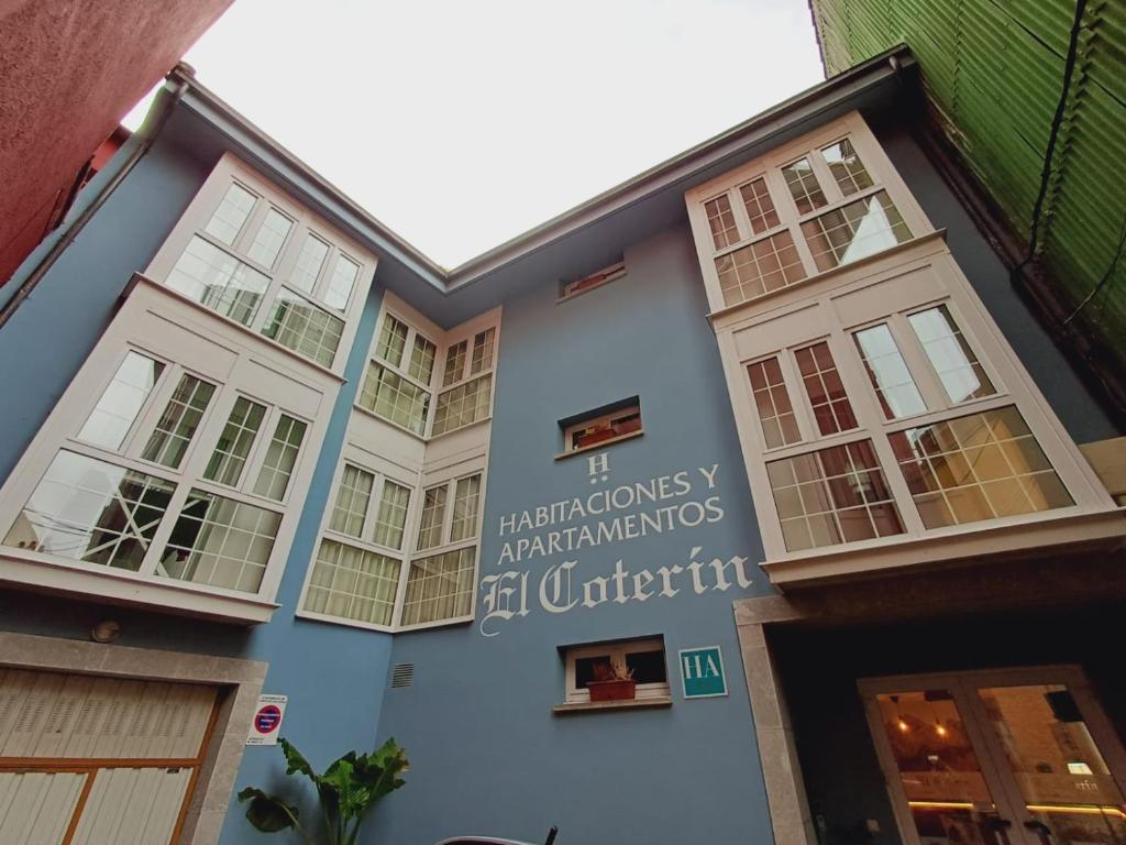 阿里纳斯·德·卡伯瑞勒斯Hotel El Coterin Apartamentos y Habitaciones的蓝色的建筑,有窗户和标志