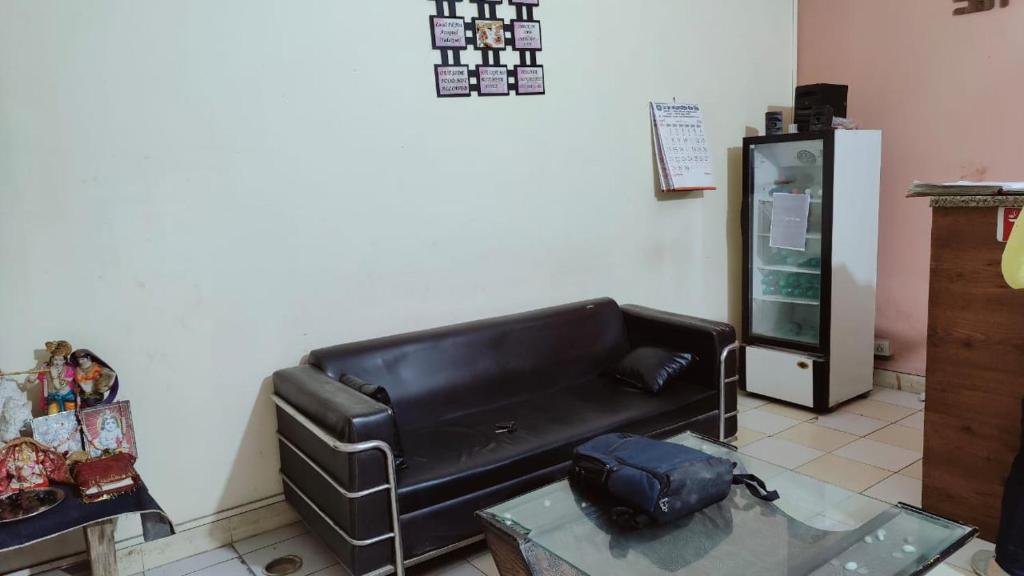 诺伊达Hotel AV Residency Sector 45 Noida的客厅配有黑色真皮沙发和桌子