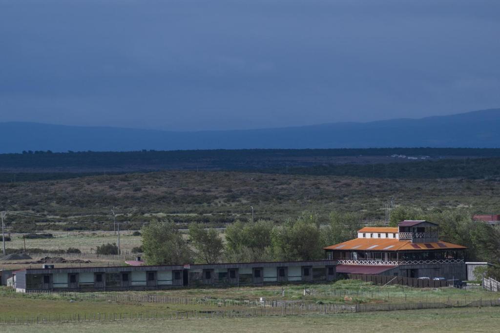 纳塔列斯港Hotel Hacienda Dorotea的一座在田野上拥有红色屋顶的建筑