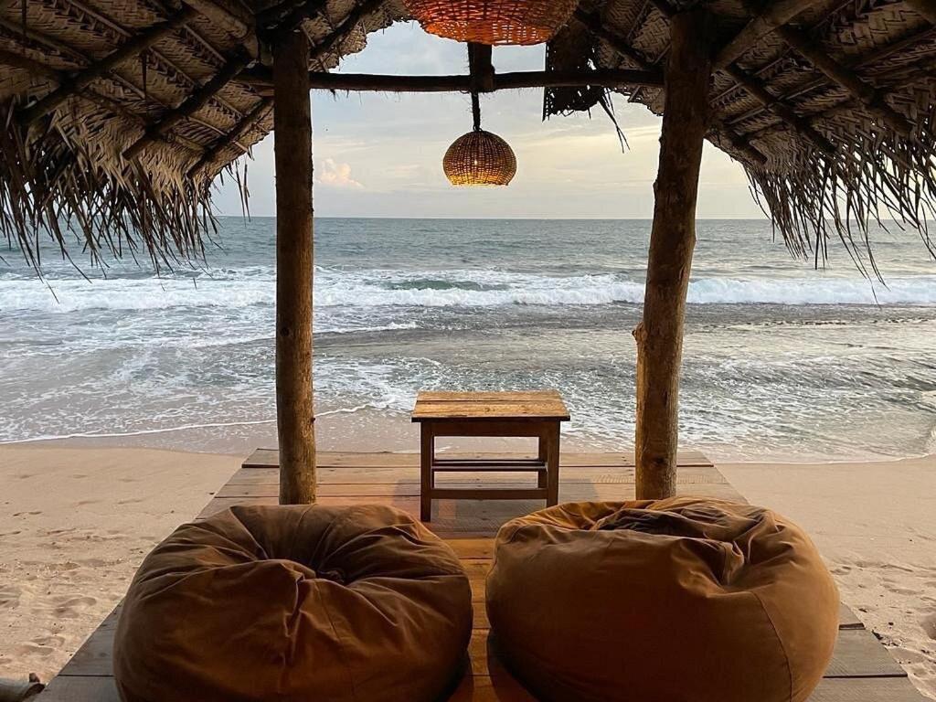坦加拉朱砂豪华帐篷度假酒店的海滩上的帐篷,配有桌子和大海