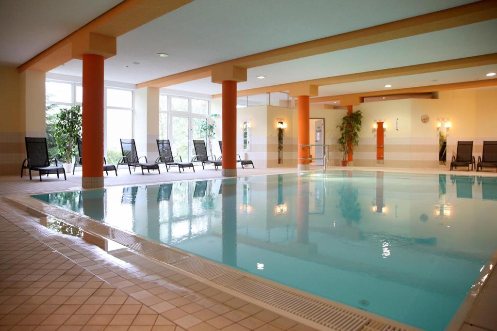 施瓦岑贝格Sonnenhotel Hoher Hahn的酒店大堂的大型游泳池,配有椅子