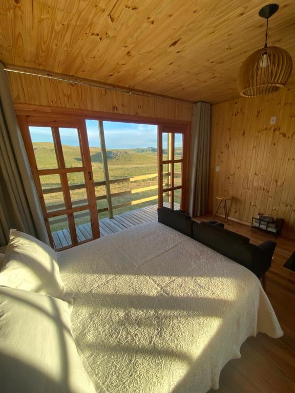 圣若泽-杜斯奥森蒂斯Chalé Campos Da Serra的一间卧室设有一张床和一个大窗户