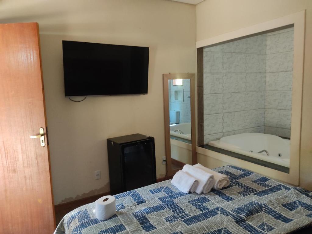 新利马Pousada Rota dos Macacos的一间卧室配有一张带浴缸的床和一台电视。