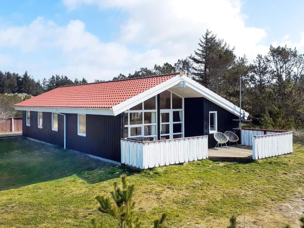 克利特默勒Holiday Home Ajs Mølls的蓝色的房子,有红色的屋顶和院子