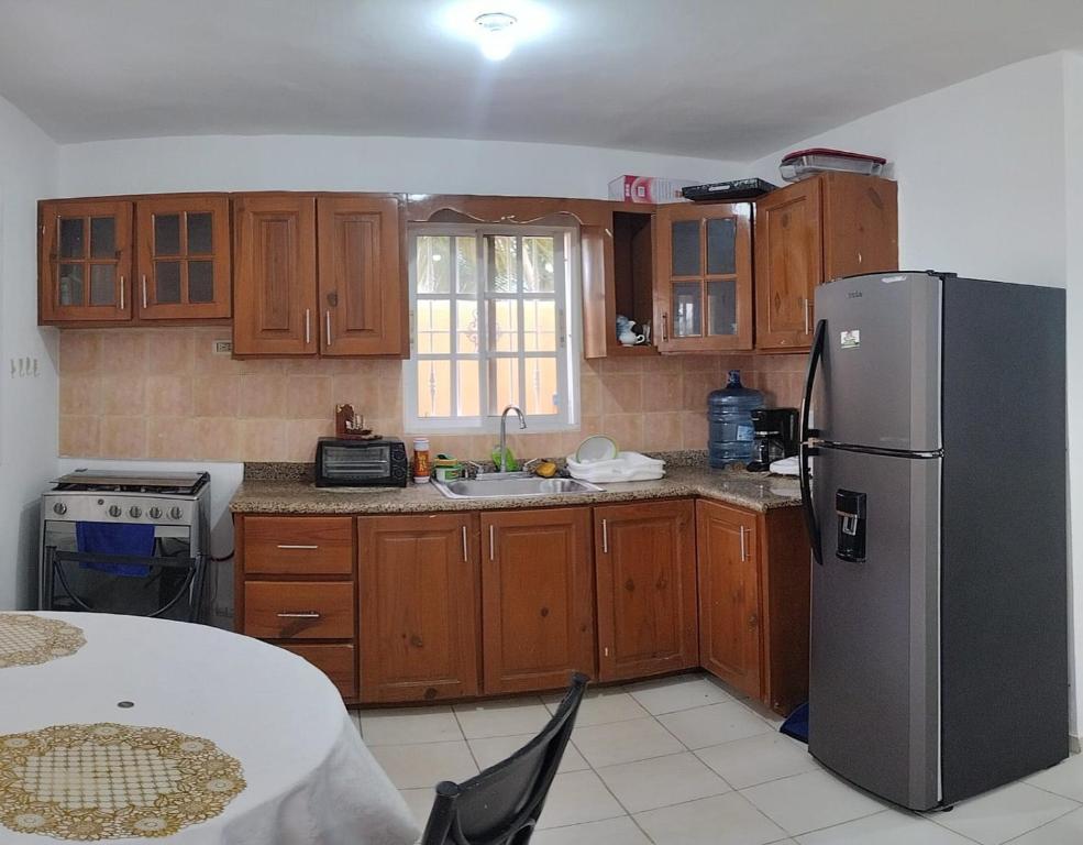 蓬塔卡纳Hostal Palmas De Punta Cana的厨房配有木制橱柜和不锈钢冰箱。