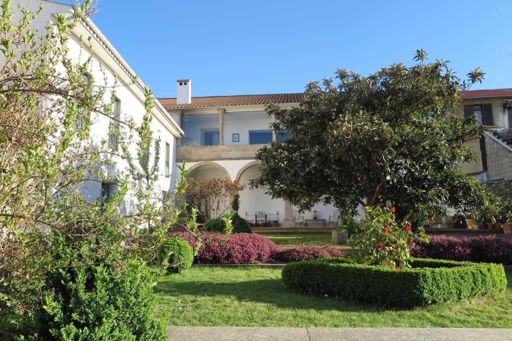 布拉干萨圣玛丽亚太阳旅馆的一座树木和灌木丛的建筑前的花园