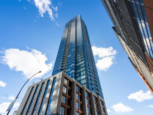 蒙特利尔Spectacular Skyline Views - Downtown Montreal - Luxury Condo & Penthouse的一座高大的玻璃建筑,拥有蓝色的天空和云朵