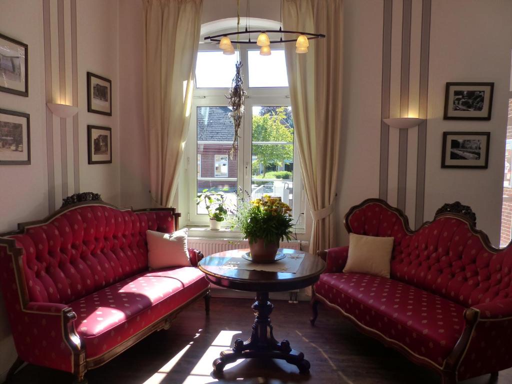 斯洪保因霍泰Hotel am Rathaus的客厅配有红色的沙发、桌子和窗户