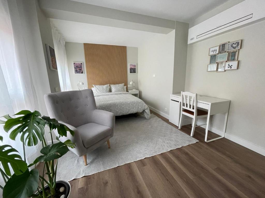 马德里Rooms Madrid Río的一间卧室配有一张床、一把椅子和一张书桌