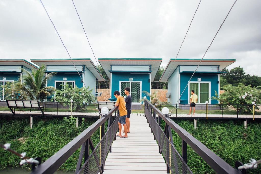 Ban Tha MakGreen Country Park Resort的一对夫妇站在一座房子前面的桥上