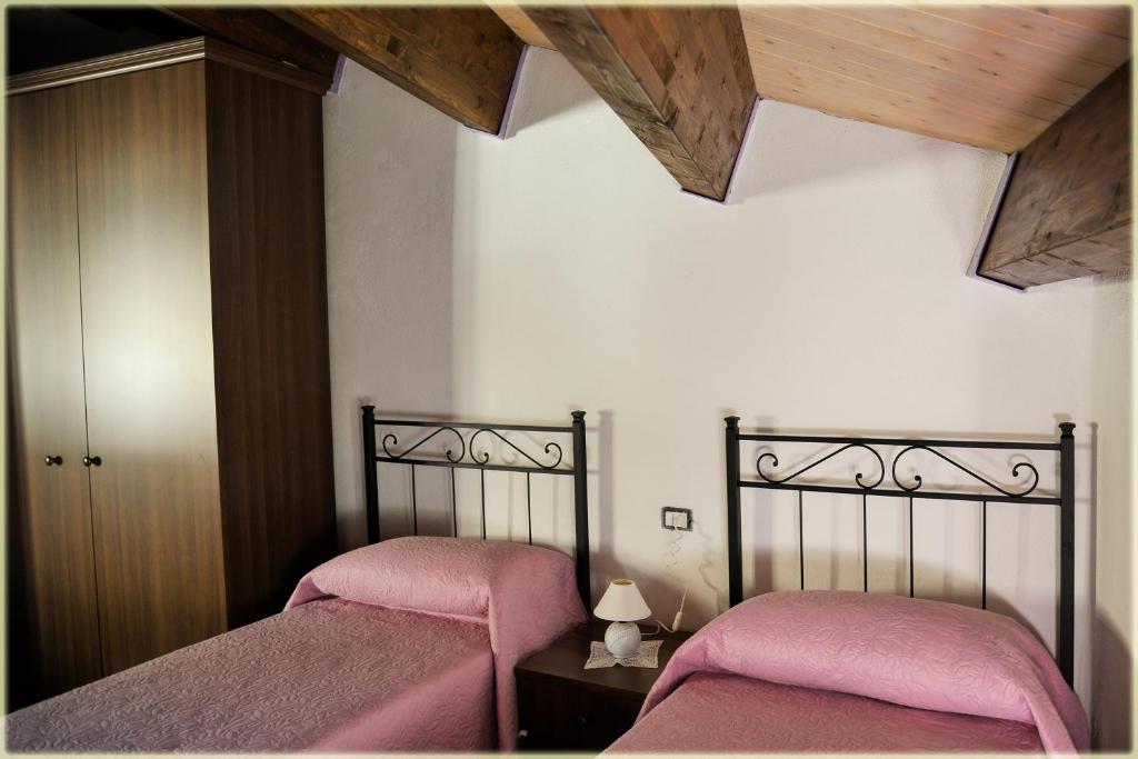 皮耶特拉佩尔托萨Il Palazzo del Barone - Stanza dei Ravelli的一间卧室配有两张带粉红色床单的床