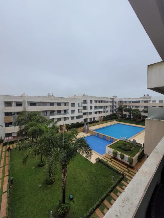 曼苏里亚Résidence Paradise Beach Aves piscine的一座带游泳池和棕榈树的公寓以及一座建筑