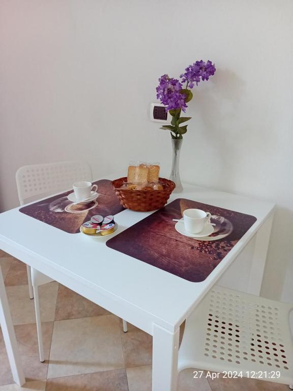 斯培西亚IL GIARDINO的一张带一篮面包和花瓶的白色桌子