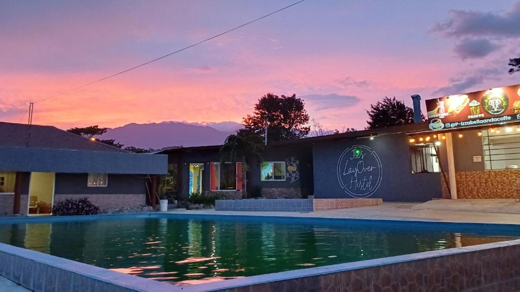 下博克特Joe's Layover Hostel Boquete的一座享有日落美景的建筑前的游泳池