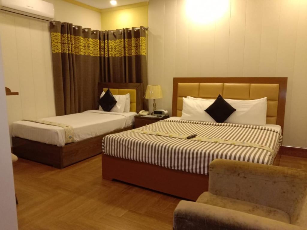 拉合尔EXPRESS HOTEL的酒店客房,配有两张床和椅子
