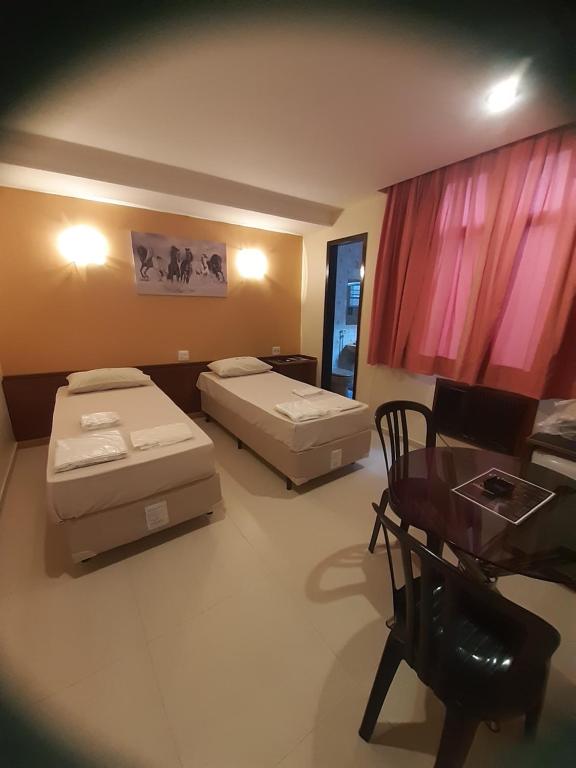 里约热内卢巴拉圭酒店（仅限成人入住）的客房设有两张床、一张桌子和一张桌子。