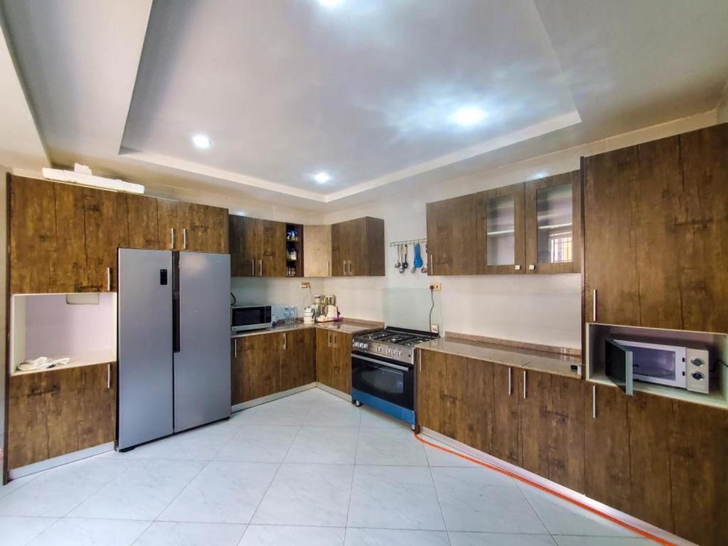 阿布贾Cozy And Serene Studio Apartment的一个带木制橱柜和冰箱的大厨房