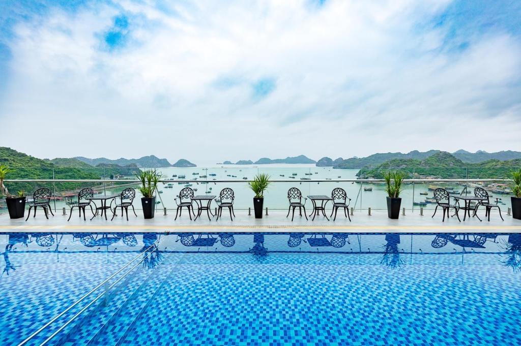 吉婆岛Cat Ba Paradise Hotel- Pool & Sky Bar的一个带椅子的游泳池,享有水景