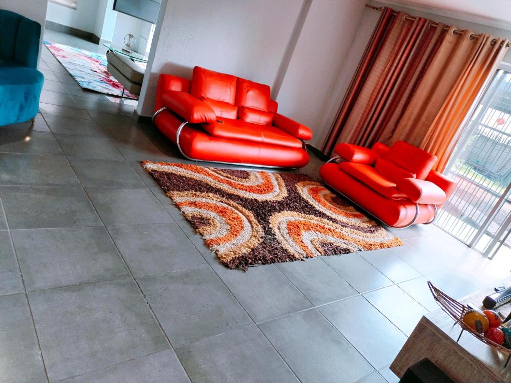 塞昆达Reutlwane Gardens house的客厅配有2把红色椅子和地毯