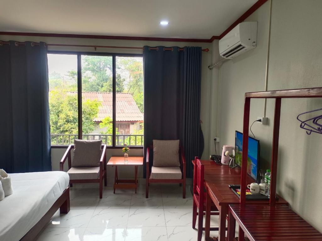 万荣Vang Vieng Champa Hotel的酒店客房带一张床、一张桌子和椅子