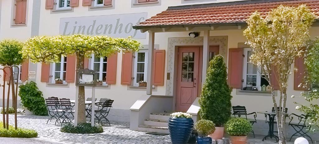 OberaurachHotel garni Lindenhof im Steigerwald的一座配有粉红色门、桌子和椅子的建筑