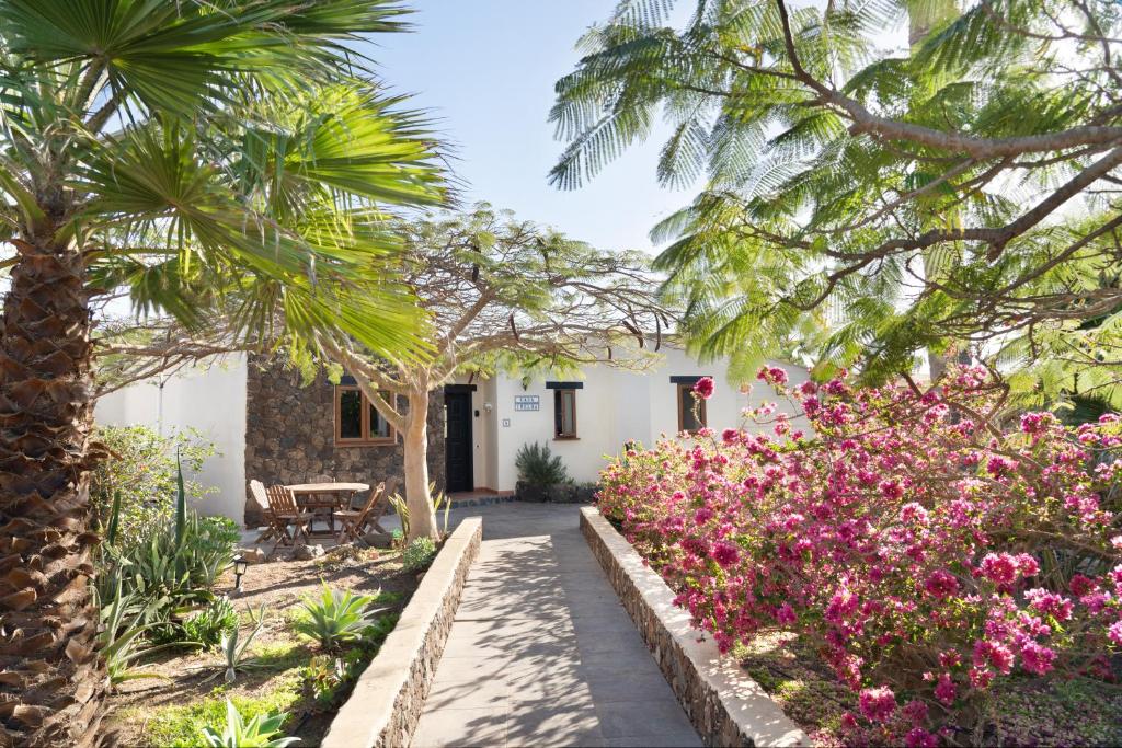 维拉韦德Villa Helda - Private Bedroom in a Shared Villa of 4 bedroom的种有粉红色花卉和棕榈树的花园