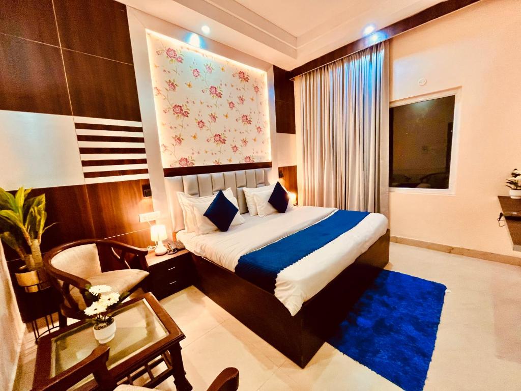 阿姆利则Hamilton Hotel & Resort, Near Golden Temple Parking Amritsar的配有床、椅子和桌子的酒店客房