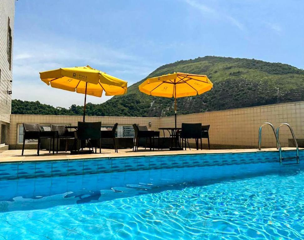 里约热内卢Riale Vilamar Copacabana的一个带两把遮阳伞和桌椅的游泳池