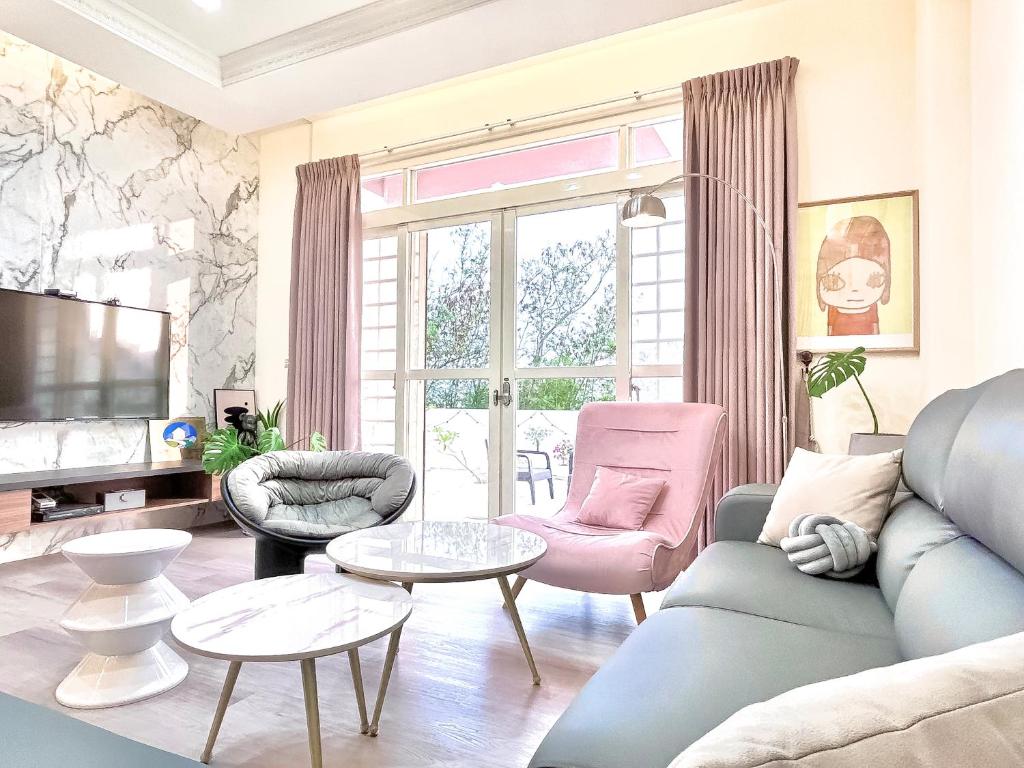 马公沙沙民宿的客厅配有蓝色的沙发和粉红色的椅子