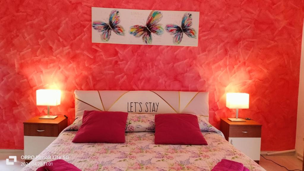 伦蒂尼Rubino house的一间卧室配有一张红色墙壁的床和两盏灯。