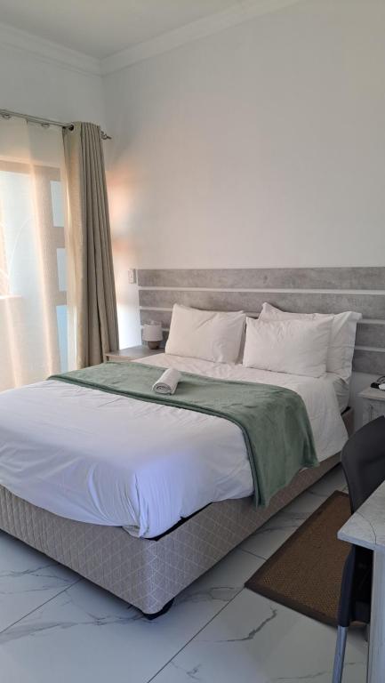鲸湾港Onamungundo Backpackers的一间卧室配有一张大床和灰色床头板