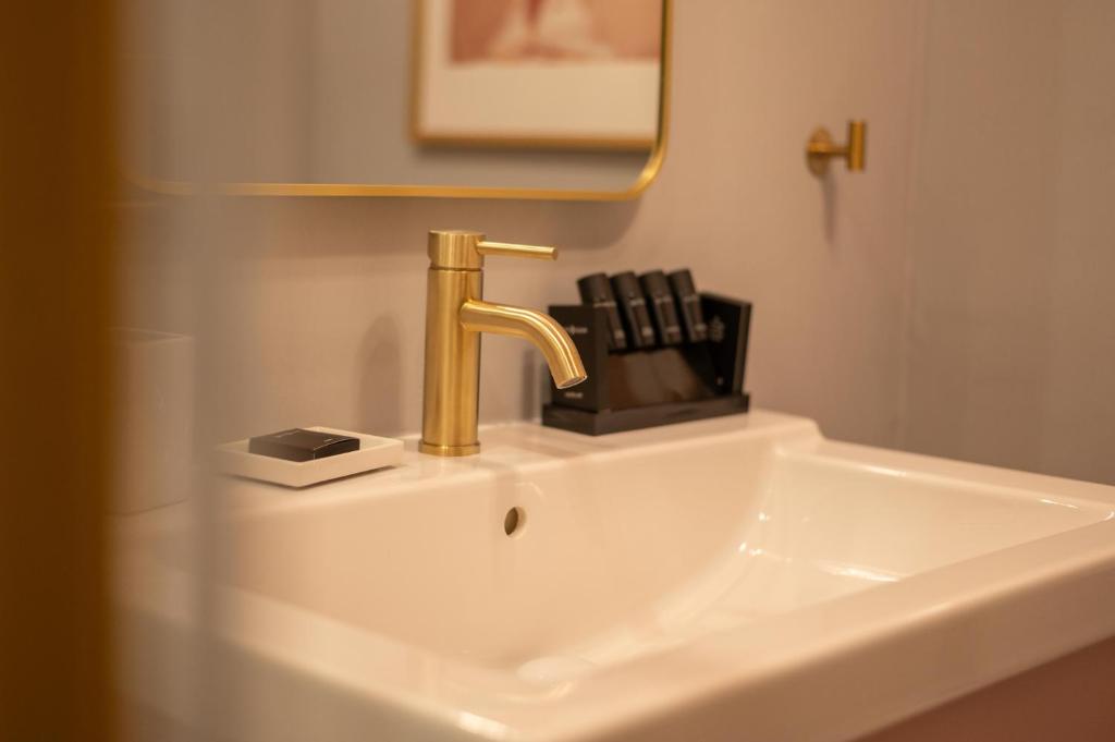 伊西翁L Suites The Writer's House的浴室水槽上装有金色水龙头