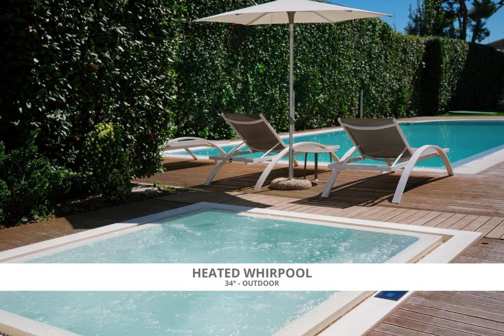 代森扎诺-德尔加达Hotel Palazzo del Garda & Spa的游泳池旁的两把椅子和一把遮阳伞