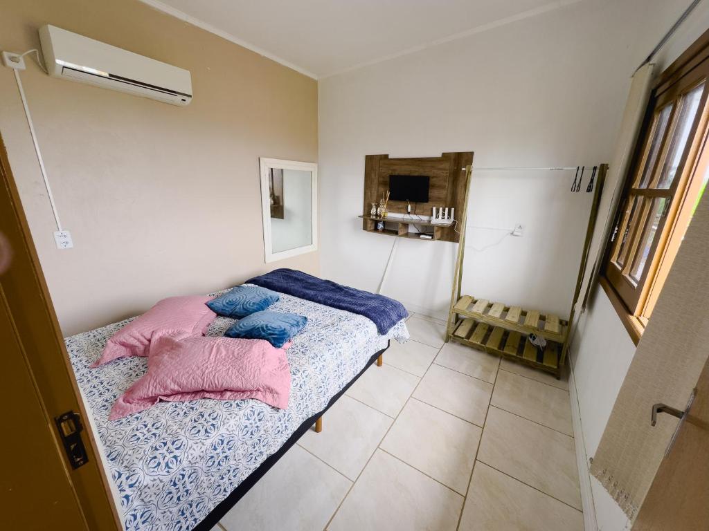 帕苏迪托雷斯Bella Praia apartamento Tartaruga的一间卧室配有一张带蓝色和粉红色枕头的床