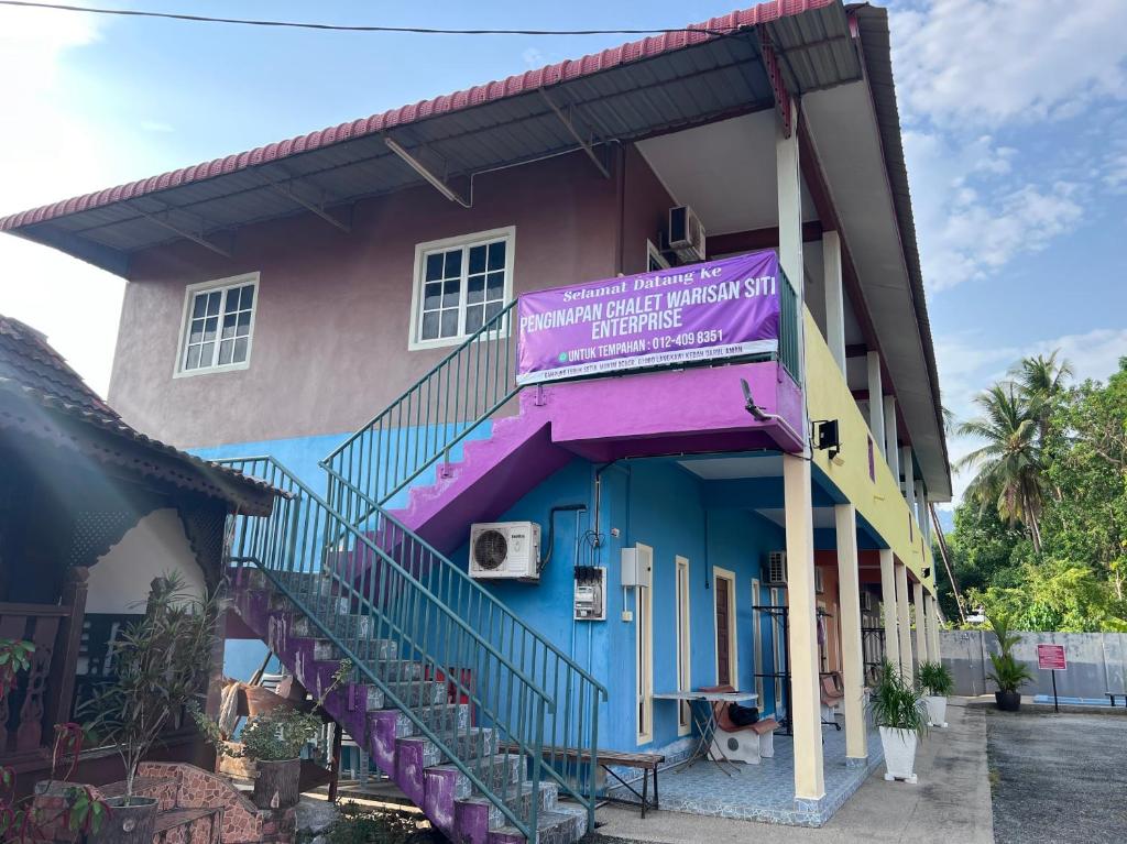 巴东马士力OYO 90967 Homestay Chalet Warisan Siti的一座色彩缤纷的建筑,上面有紫色的标志