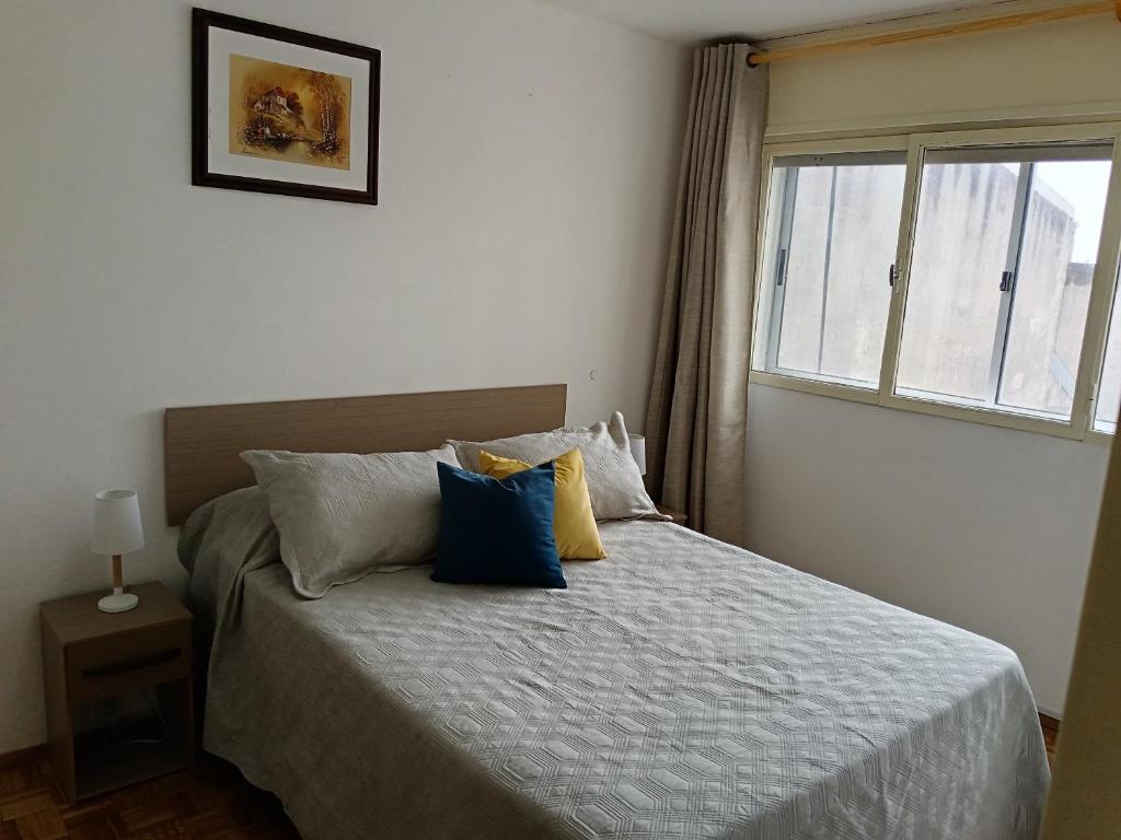 蒙得维的亚Apartamento para cuatro personas totalmente equipado的一间卧室配有蓝色和黄色枕头的床