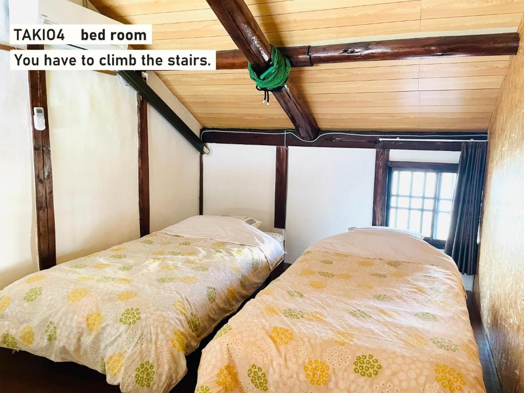 东大阪市TAKIO Guesthouse - Vacation STAY 12211v的一间卧室设有两张床和木制天花板