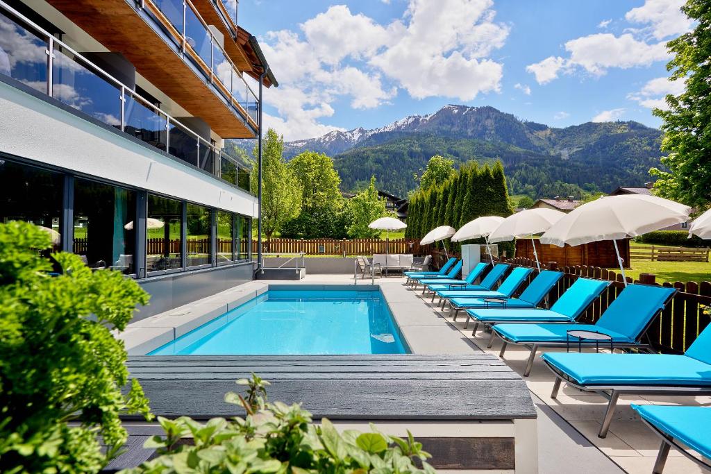 卡普伦HOTEL SONNBLICK Kaprun Salzburg - incl Zell am See-Kaprun Summercard的一个带躺椅和遮阳伞的酒店游泳池