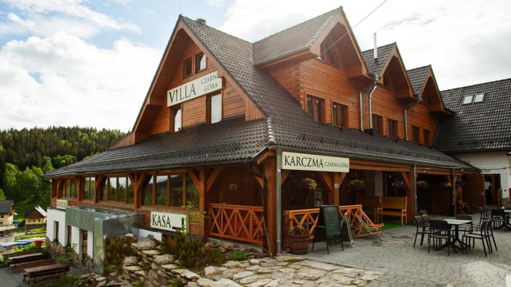 斯托尼拉斯奇Karczma Czarna Góra - Czarna Góra Resort的一座大型木制建筑,前面设有一张桌子