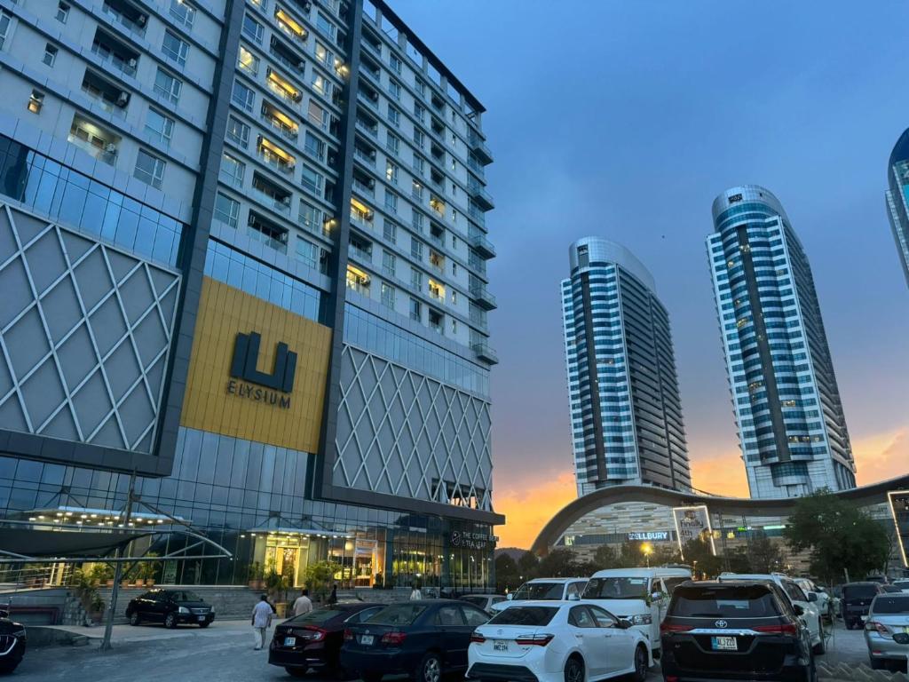 伊斯兰堡LMY Elysium Designer Luxury Apartments Facing Centaurs Mall Islamabad的两个高楼前的一个停车位