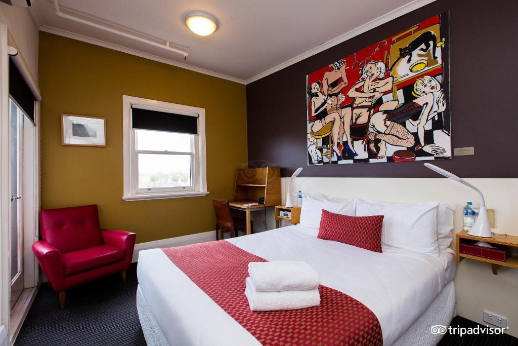墨尔本Tolarno Hotel - Chambre Boheme - Australia的一间卧室配有一张大床和一张红色椅子