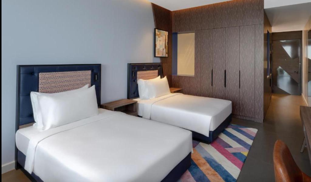 迪拜Hyatt Centric Jumeirah - Dubai Twin Room - UAE的酒店客房设有两张床和一张桌子。