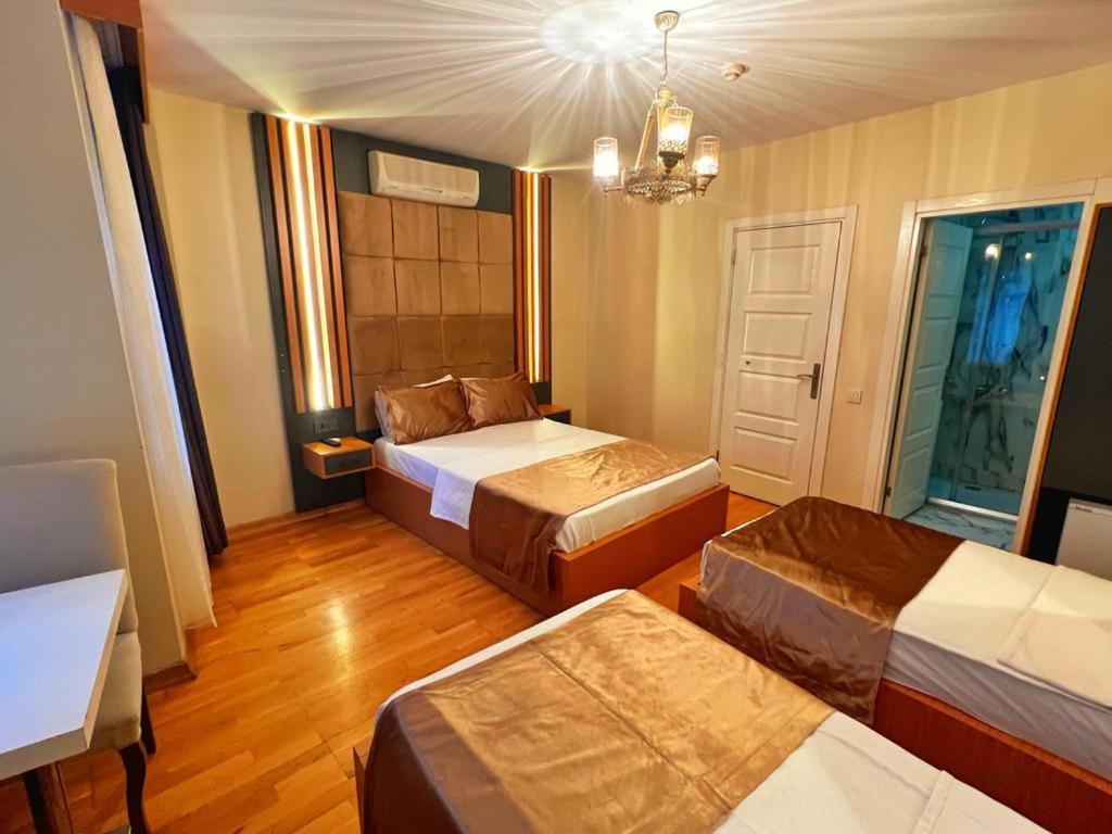 伊斯坦布尔Taksim Cetinkaya Suite的带三张床和吊灯的客房
