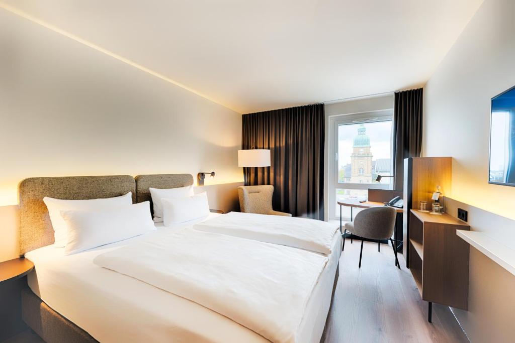 达姆施塔特Welcome Hotel Darmstadt City Center的酒店客房设有一张大床和一张书桌。