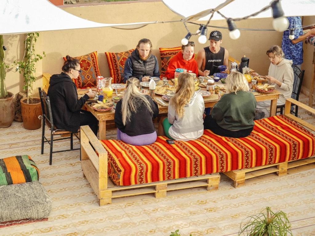 塔姆拉赫特乌兹达尔Darna Surf House Morocco的一群坐在餐桌上吃食物的人