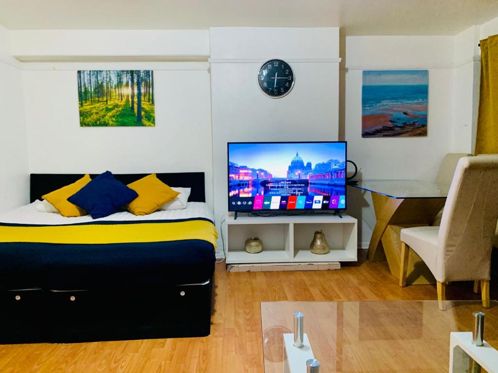 伦敦London Stratford 4 Bedrooms Apartment的一间卧室配有一张带电视和书桌的床。